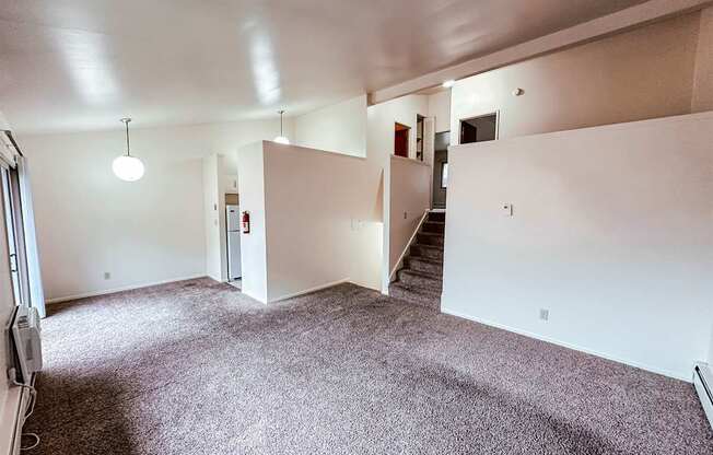 A large empty room with a staircase and a fire extinguisher.