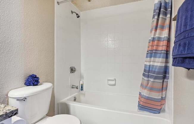 a bathroom with a toilet and a tub and a shower curtain at The Glen at Highpoint, Dallas, 75243