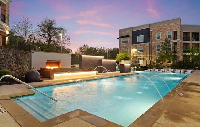 A swimming pool with a waterfall and a fireplace in the background.