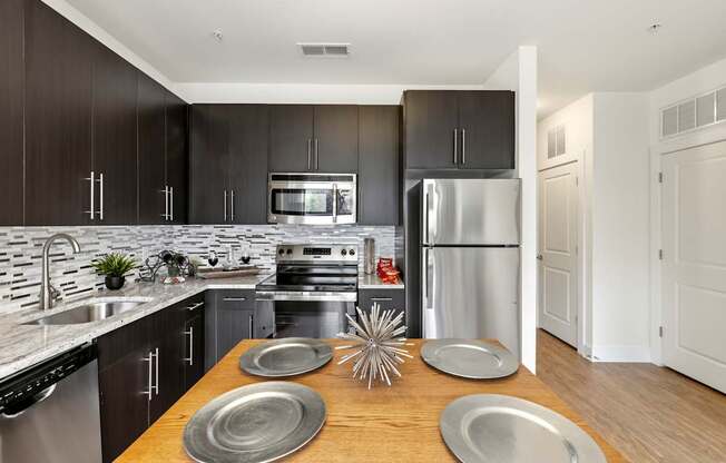 A modern kitchen with a wooden table and stainless steel appliances.