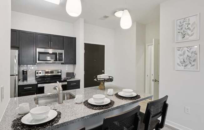 A modern kitchen with a dining table set for two.
