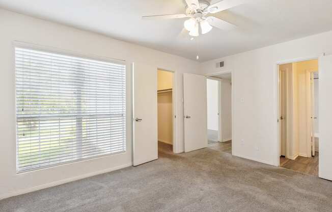 A room with a ceiling fan and carpeted floor.