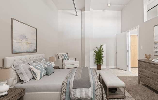 A bedroom with a bed, a bench, and a painting on the wall.