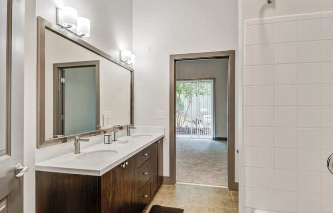 a bathroom with a sink and a mirror and a door to a shower