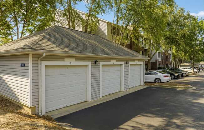 a small garage with white doors on the side of a street