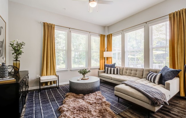 a living room with yellow curtains and a white couch at Century University City, Charlotte, NC