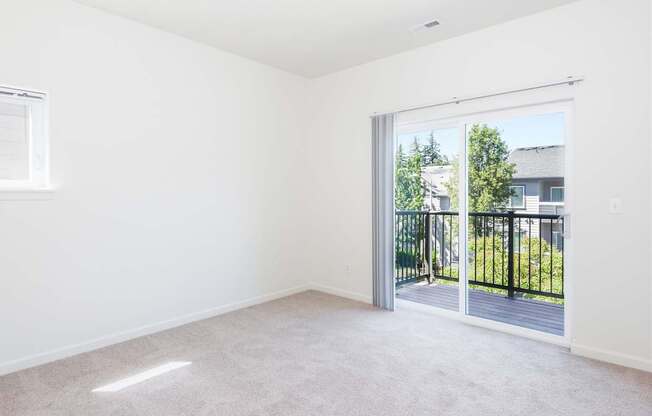 A room with a carpeted floor and a sliding glass door leading to a balcony at The Landing Apartments and Townhomes, Oregon, 97045