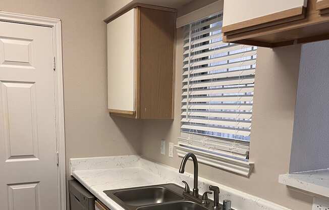 a kitchen with white cabinets and a sink and a window