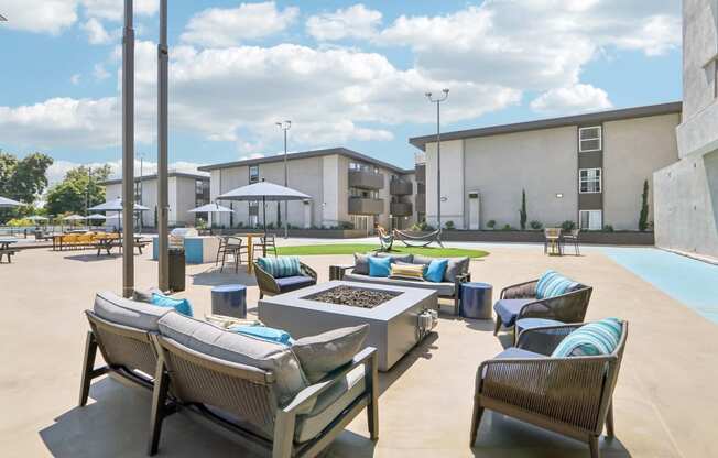 an outdoor lounge area with tables and chairs and a fire pit