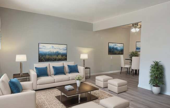 A living room with a white couch, a coffee table, and a painting on the wall.
