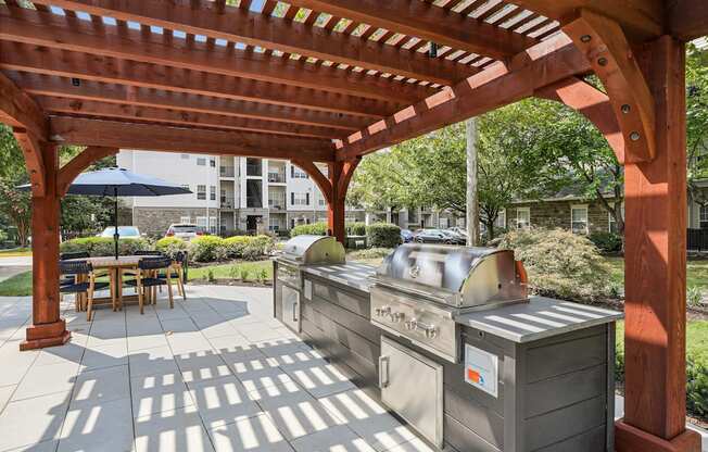 a covered patio with two grills and a wooden pavilion