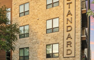 The Standard building has a brick facade and is surrounded by a landscaped area.