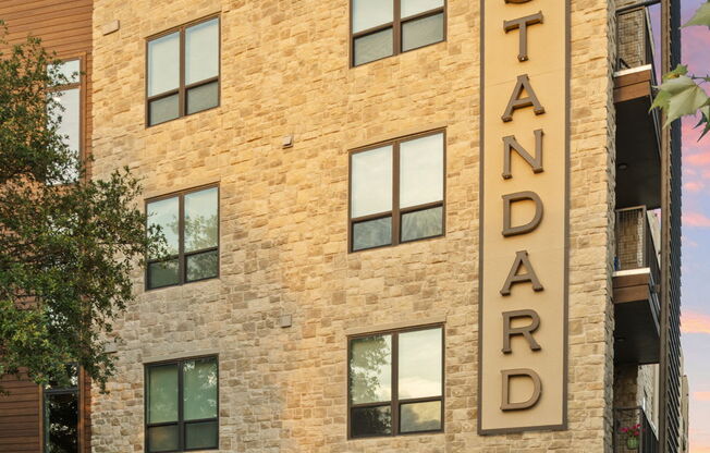 The Standard building has a brick facade and is surrounded by a landscaped area.