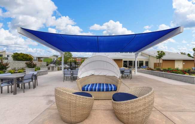 Outdoor Lounge with Wicker Chair, Blue Sun Cover, Tables and Chairs, Blue Sky with Clouds