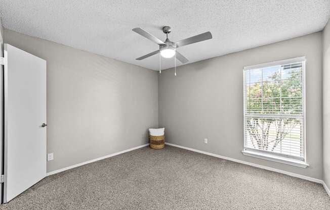 A room with a ceiling fan and a window with blinds.