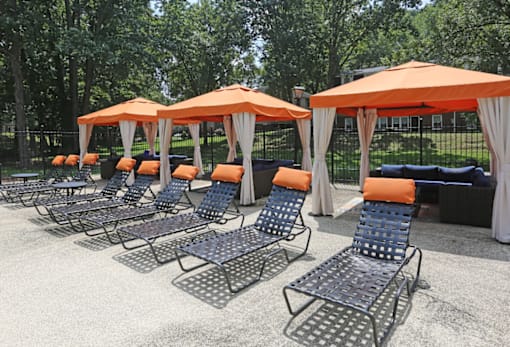 a row of chaise lounge chairs with orange umbrellas