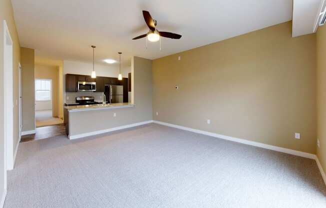 spacious living room with a ceiling fan and a kitchen