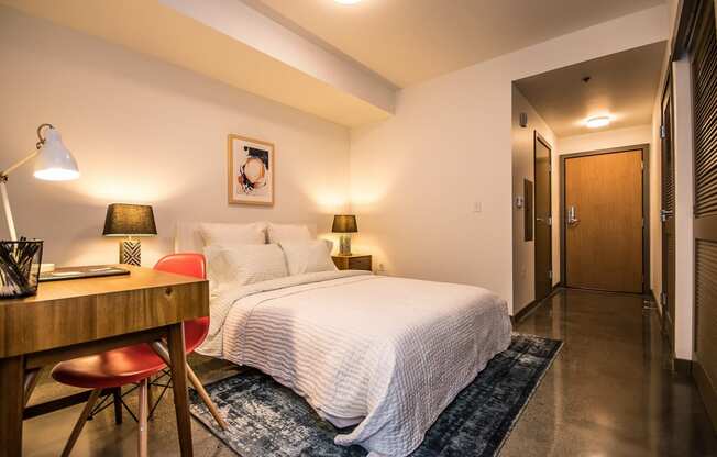 Two Bedroom Apartments in Portland, OR - Corbett Heights - Oversized Bedroom with Polished Concrete Flooring, Wood Doors, Queen Bed, Floor Rug, and Desk