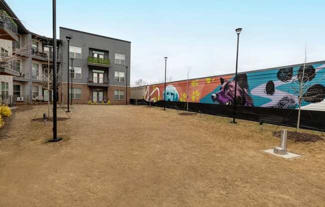 a mural on the side of a building with a dirt road