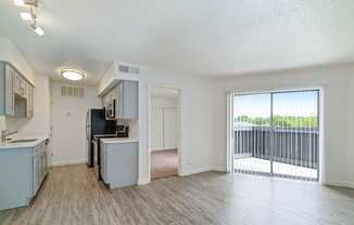 an open kitchen and living room with a sliding glass door to a balcony