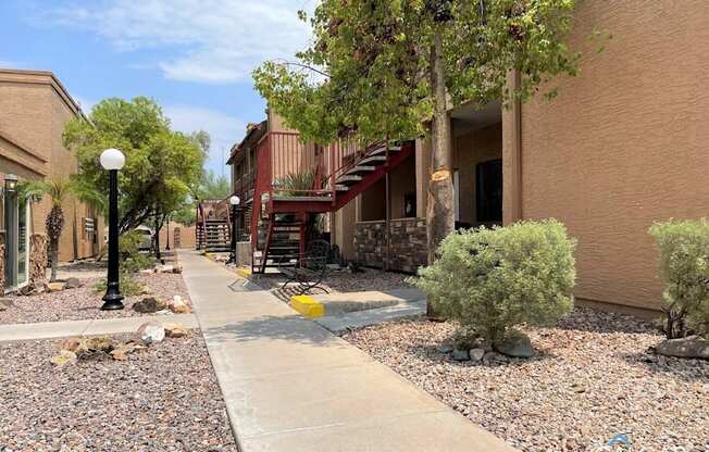 A walkway with a yellow line in front of a building with a tree on the left.