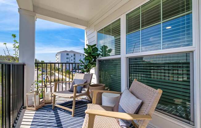 a porch with two chairs and a table and a window at Altis Grand Suncoast Apartments, Florida