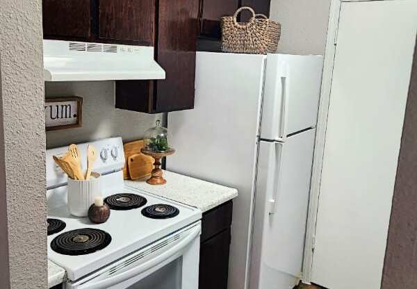 A kitchen with a white stove top oven and a white refrigerator.