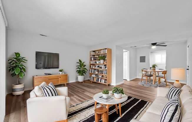 A living room with a white couch, a wooden coffee table, and a television on the wall.