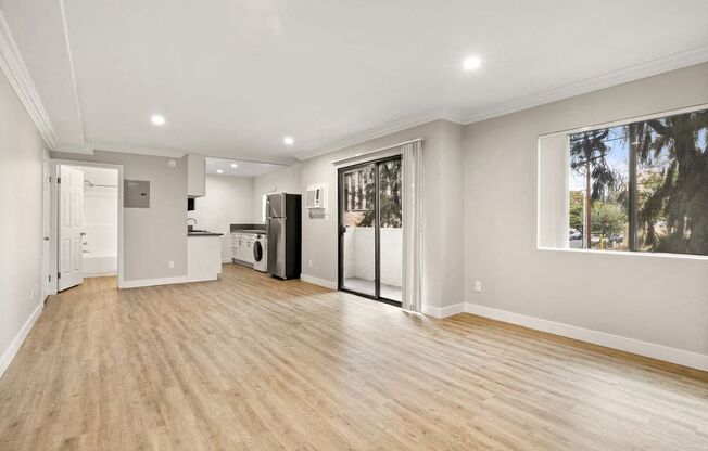 A spacious room with wooden flooring and a washer and dryer in the corner.