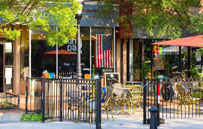 A restaurant with tables and chairs is surrounded by a black fence.