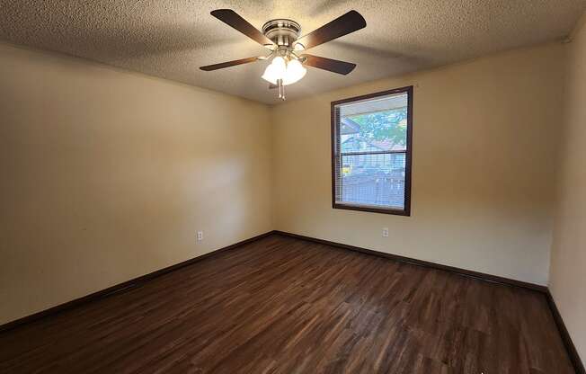 the living room of a home with wood floors and a ceiling fan