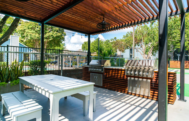 a patio with a picnic table and a grill