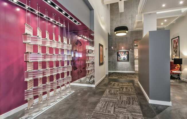 a long hallway with a pink wall and a glass case with pink and white bottles