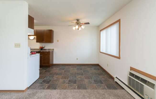 the living room and kitchen of an apartment with a ceiling fan. Fargo, ND Islander Apartments