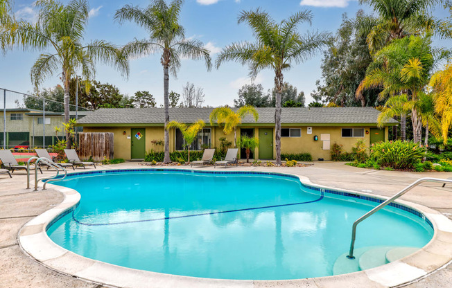 a swimming pool in front of a house with palm trees