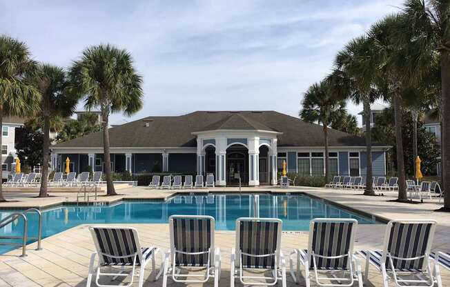 A pool with chairs and a building in the background.