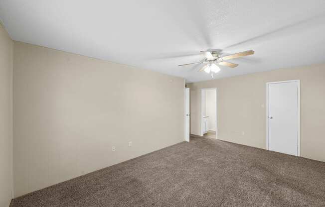 an empty living room with carpet and a ceiling fan at Brookside Apartments, Hewitt, TX