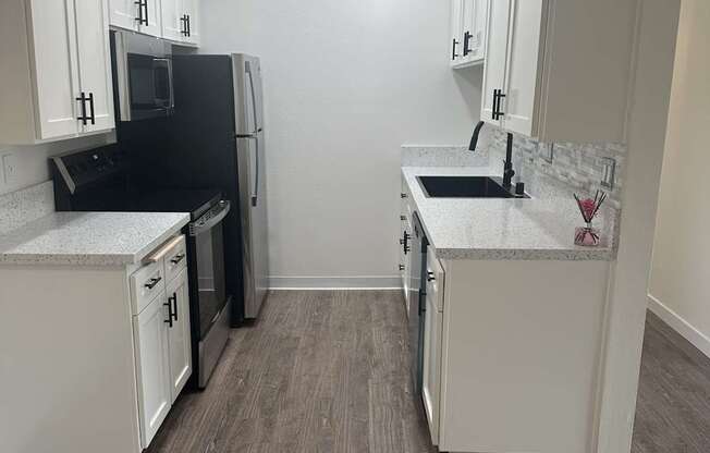 A kitchen with white cabinets and a black fridge. at Camino de Oro Apartments, Torrance, CA, 90505