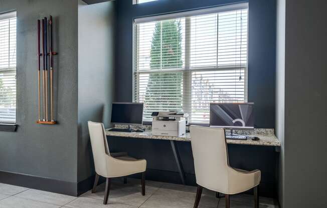 an office with two chairs and a desk with a computer and a window