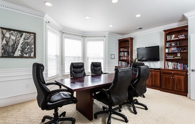 a conference room with a table and chairs and a television
