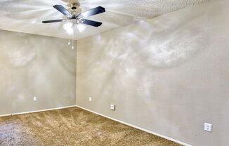 an empty room with a ceiling fan and carpet