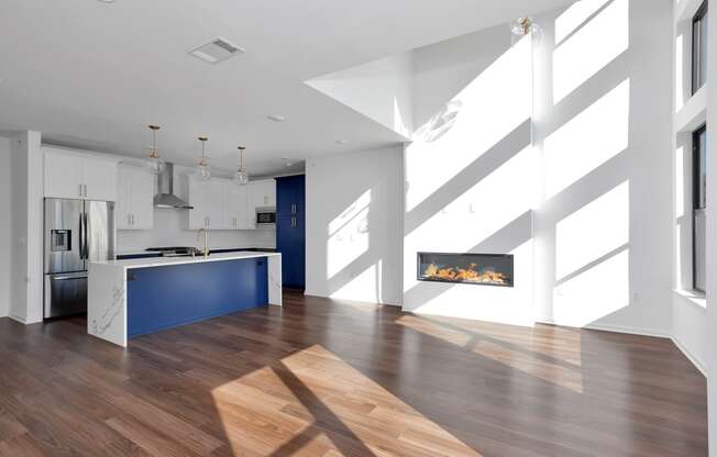 a large white kitchen with a blue island and a fireplace