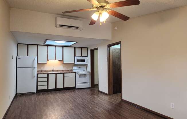 a kitchen with white appliances and a ceiling fan