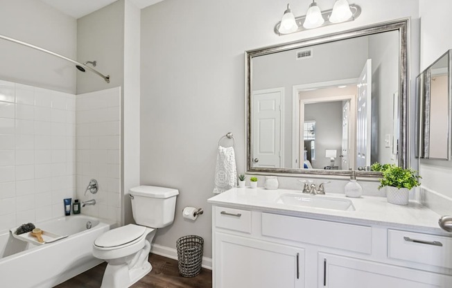 A white bathroom with a large mirror and a white bathtub.