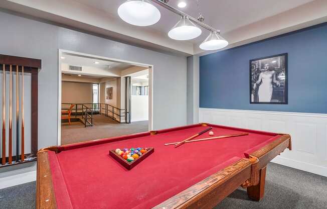 a red pool table in a blue room with a black and white picture on the wall