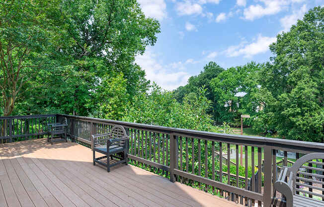 a large deck with benches overlooking a pond and trees