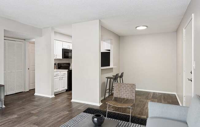 Model Living Room with Wood-Style Flooring and View of Kitchen at Grand Pavilion Apartments in Tampa, FL.