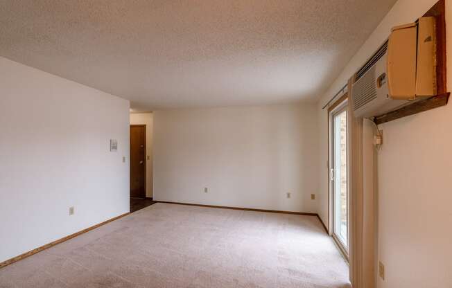 A empty living room with white walls and a window. Fargo, ND Huntington Apartments.