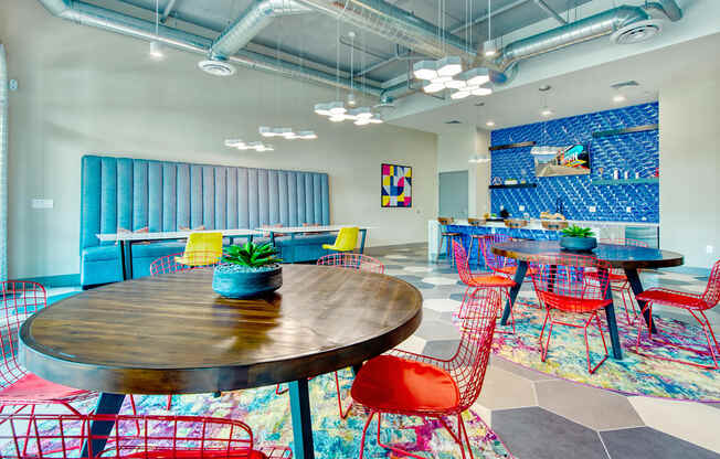 A room with a round wooden table surrounded by red chairs.