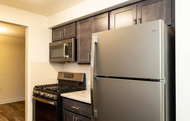 a kitchen with dark wood cabinets and stainless steel appliances